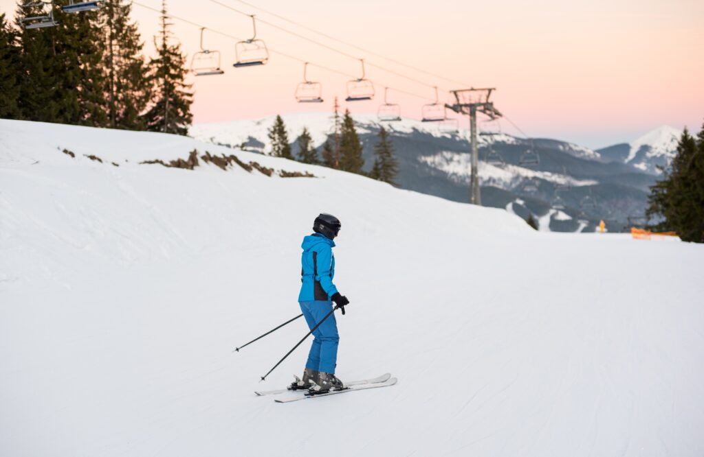 Female skier on middle of ski slope against ski lifts