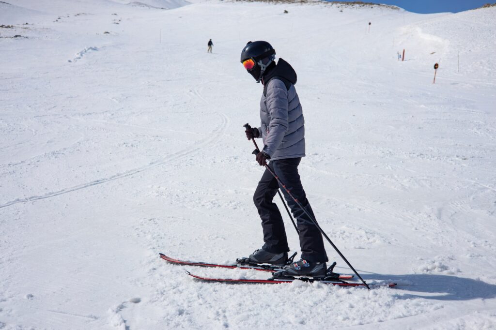 Girl in ski suit, helmet and sun mask with ski poles skiing on mountain skis girl skiing down