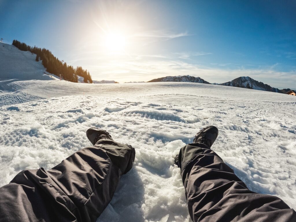 Legs view of young man looking the sunset on snow high mountains